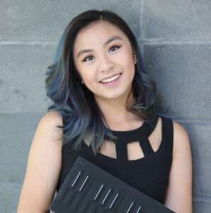 Headshot of a woman with colored hair wearing a black dress