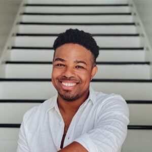 Headshot of a smiling man sitting on the staircase